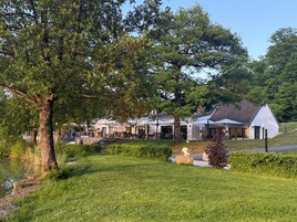 Un restaurante con terraza, un árbol grande y un edificio de fachada blanca.