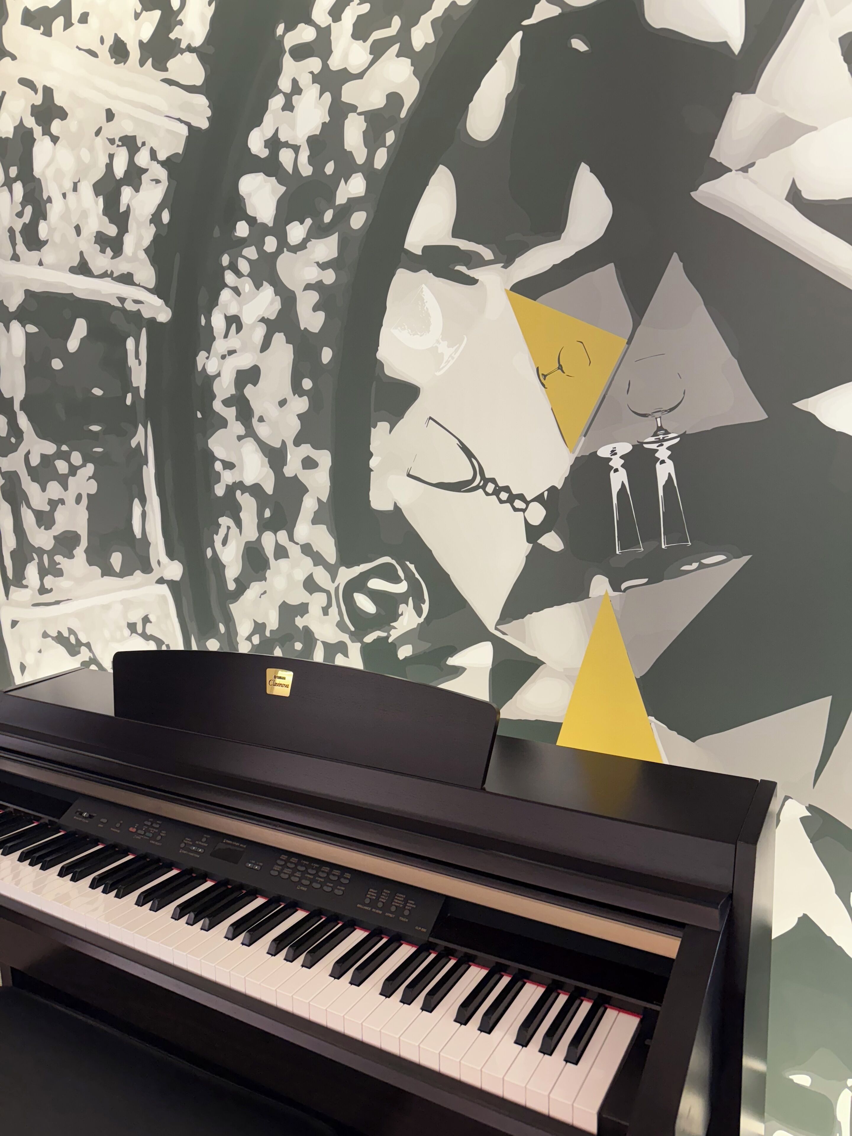 Ein Klavier vor einer Wand mit schwarz-weißem Muster.