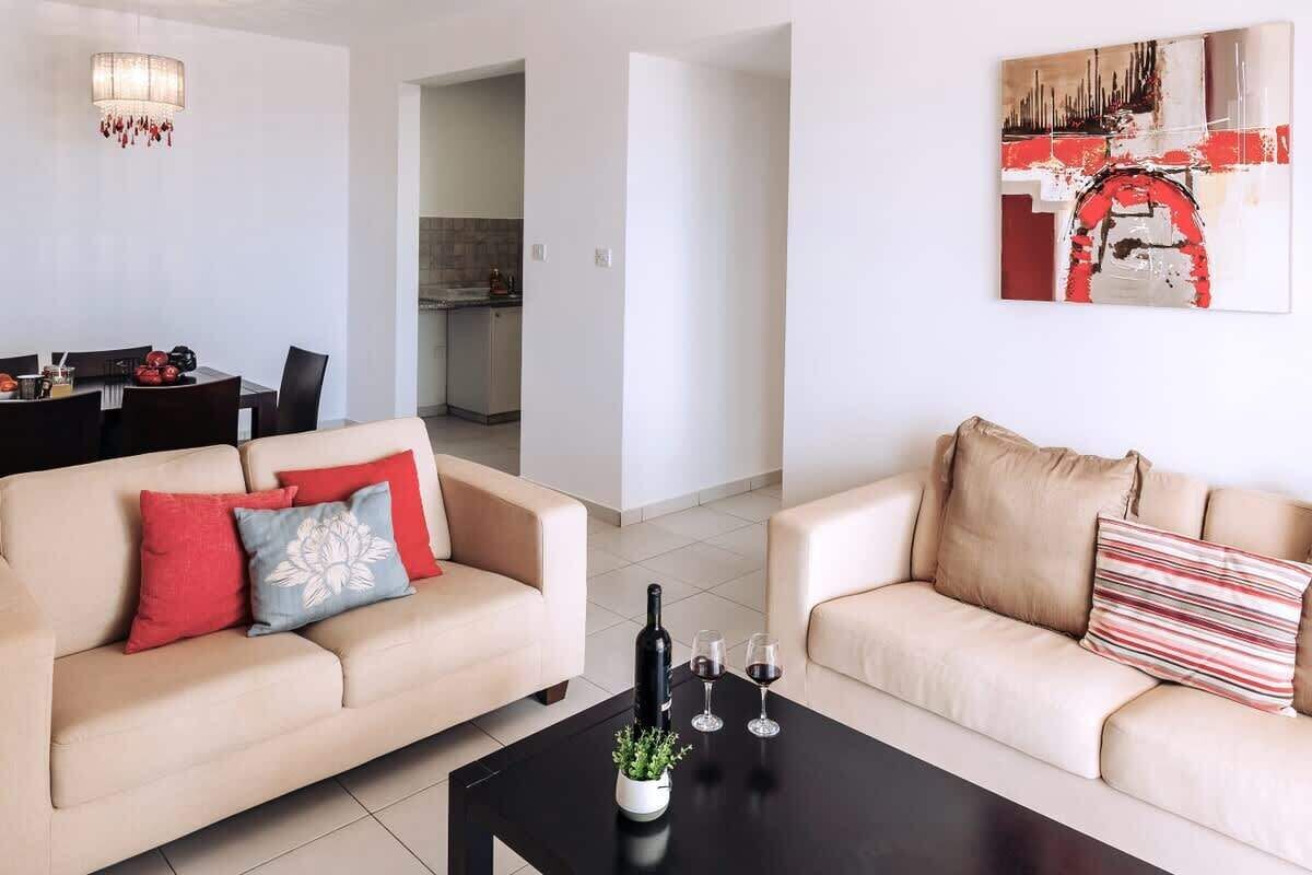 Una sala de estar con dos sofás, una mesa de comedor y una cocina al fondo.