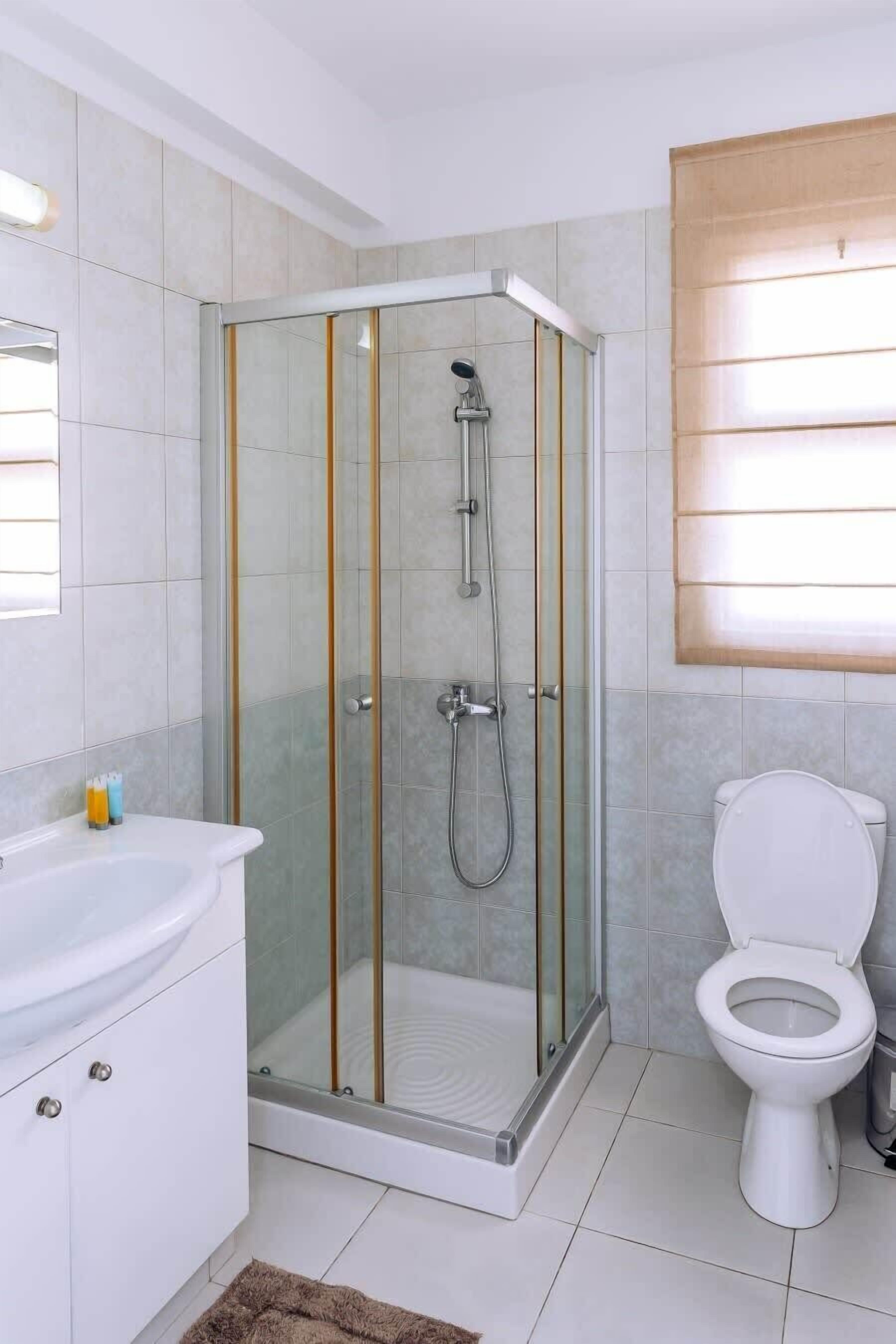 Une salle de bain moderne avec une douche à parois de verre, des toilettes blanches et un lavabo blanc.