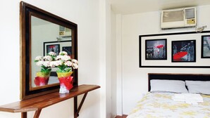 A hotel room with a bed, a nightstand with a mirror, and wall-mounted artwork. - Room 105 at Liezel's B & B in Palompon / Kalanggaman Island (PALOMPON)