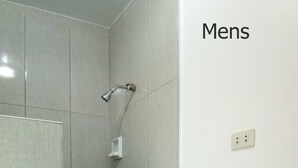 A men's bathroom with a shower, a sink, and a wall-mounted light fixture. - Room 105 at Liezel's B & B in Palompon / Kalanggaman Island (PALOMPON)