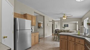 Eine moderne Küche mit einem Edelstahl-Kühlschrank, Holzschränken und einer zentralen Kochinsel mit Spüle.