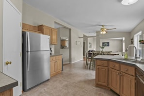 Una cocina moderna con refrigerador de acero inoxidable, gabinetes de madera y una isla central con pileta.