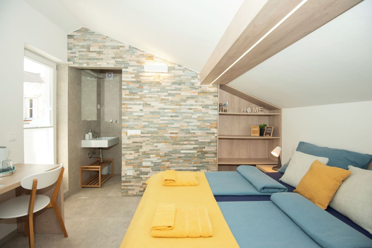 A modern bedroom with a bed, a desk, and a bathroom.