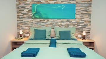 Une chambre d’hôtel avec un lit, deux tables de chevet, un téléviseur fixé au mur et un mur décoré de mosaïques.