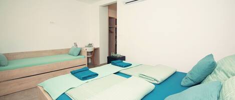 A modern bedroom with a bunk bed, a single bed, a bedside table, a mirror, and a wardrobe.