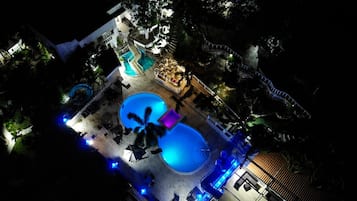 A resort with multiple swimming pools, a slide, and a bar area.