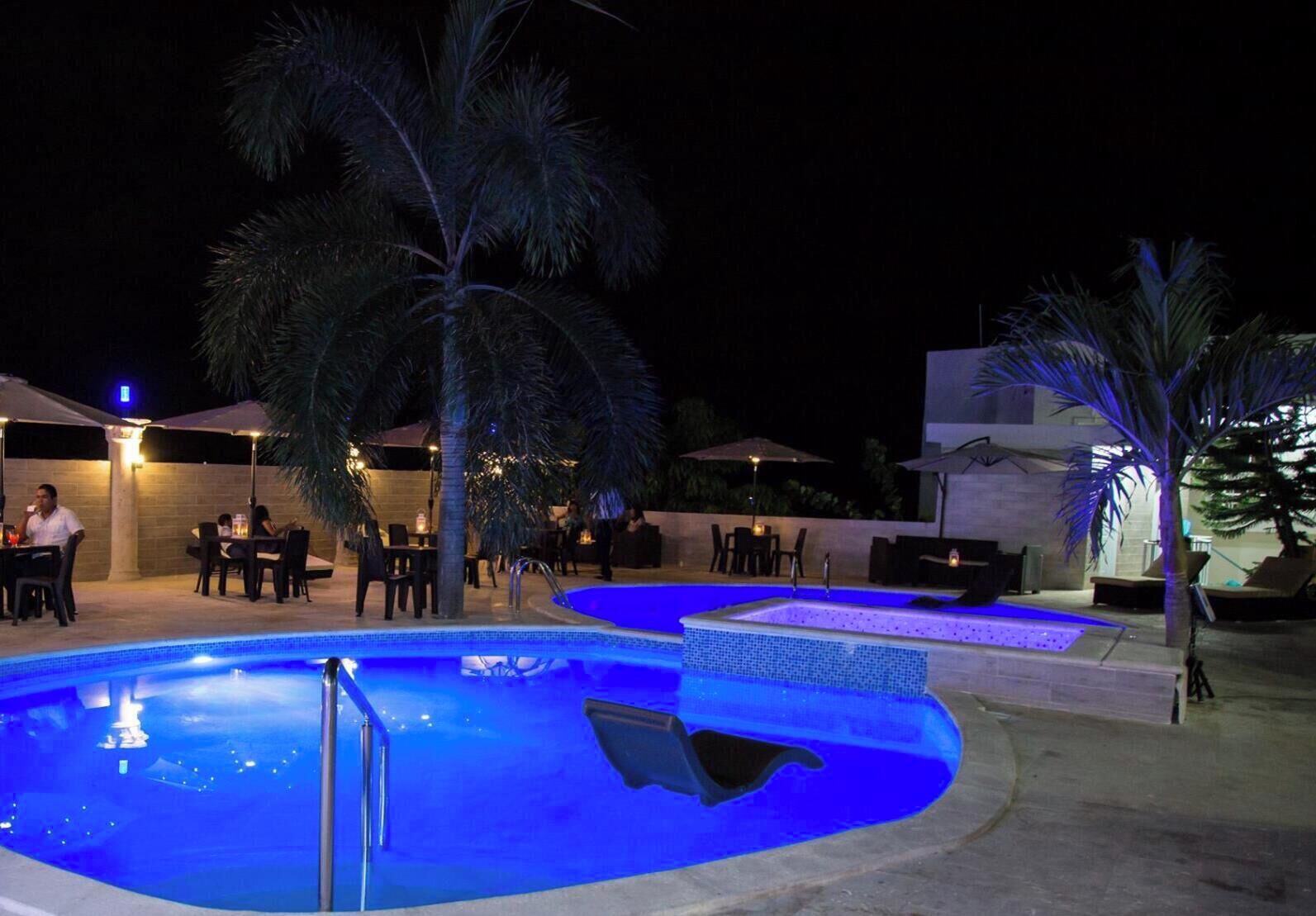 A pool area with multiple seating arrangements and palm trees.