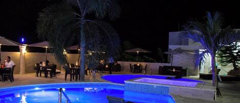 A pool area with multiple seating arrangements and palm trees.