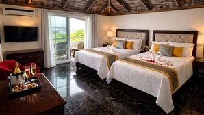 Habitación de hotel con dos camas, televisión, zona de comedor con una bandeja de comida y balcón con una silla.