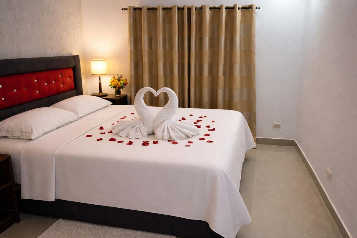 A hotel room with a bed, a nightstand, a lamp, and a curtain.