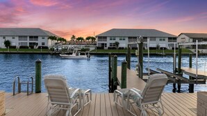 A waterfront hotel with a dock, lounge chairs, and a view of the water. - Entire Waterfront Duplex - Pool & Spa - 4BR/4BA (Cape Coral)