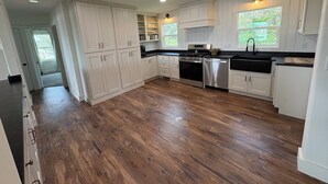 A spacious kitchen with white cabinets, a stainless steel stove, and a black countertop.