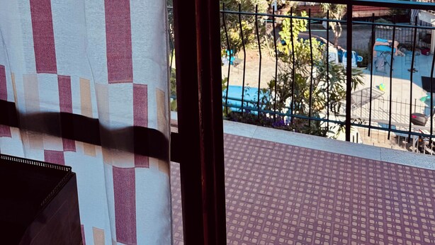 Un balcón con vista al mar y al follaje.