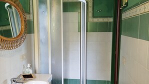 Un baño con cabina de ducha, un lavabo con espejo y una alfombra de madera.