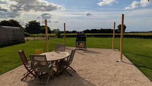 An outdoor patio with a gravel surface, surrounded by a grassy field.