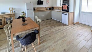 A spacious kitchen with a wooden dining table, modern appliances, and pendant lighting.