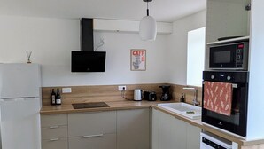 A compact kitchen with a refrigerator, microwave, oven, and coffee maker.