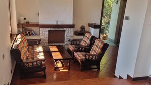 A cozy living room with a fireplace, wooden furniture, and a view of the outdoors.