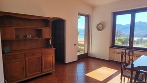 A kitchen with wooden cabinets, a dining table with chairs, a view of mountains through a window, and a door leading outside.