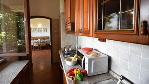 A kitchen with wooden cabinets, a microwave, and a window with a view of the outside.