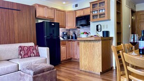A compact kitchen with wooden cabinets, a black refrigerator, and a small island with a sink.