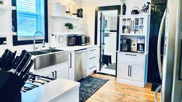 Una cucina moderna con mobili bianchi, elettrodomestici in acciaio inossidabile e una combinazione di colori bianco e nero.