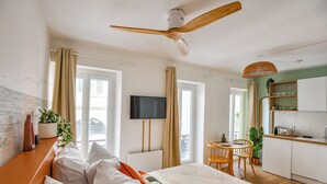 Una habitación de hotel moderna con cama, televisor, zona de comedor y cocina.