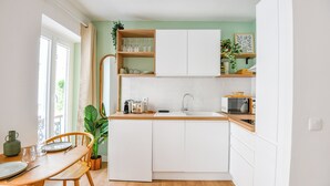 Una cocina compacta con armarios blancos, una encimera de madera y un ventanal que proporciona luz natural.