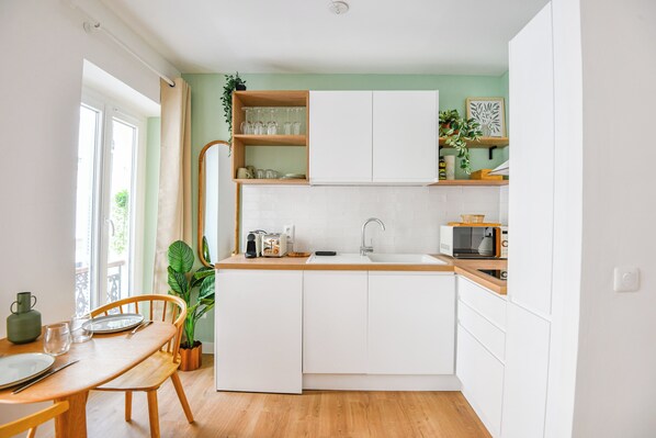 Una cocina compacta con armarios blancos, una encimera de madera y un ventanal que proporciona luz natural.