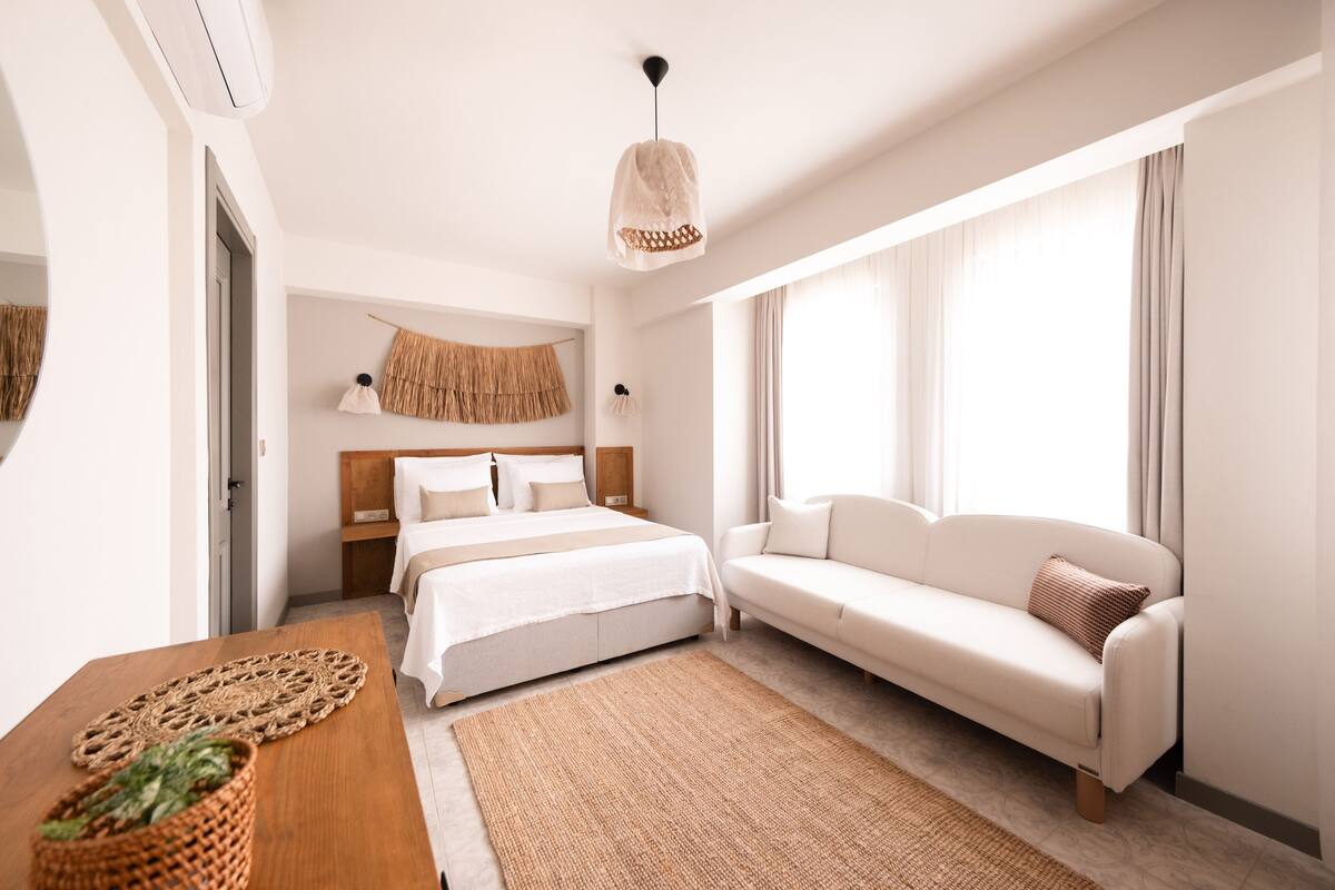 Una habitación de hotel moderna con una cama, un sofá, una mesa de madera y una lámpara colgante.