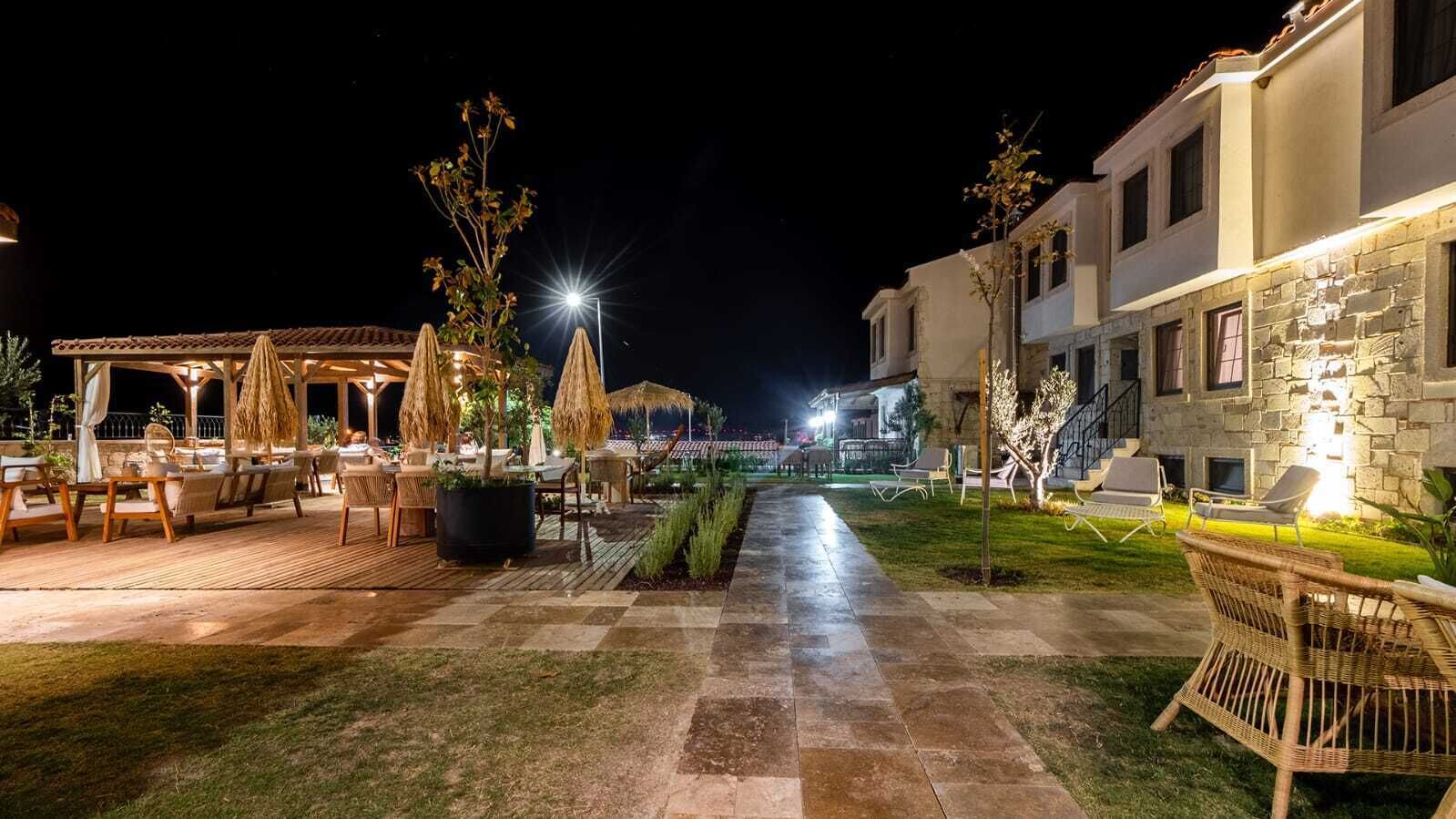 A well-lit outdoor patio area with seating arrangements and a pathway leading to a building.
