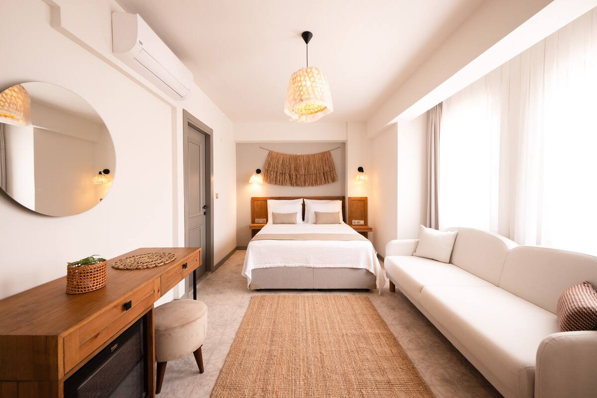 Un dormitorio moderno con cama, sofá, escritorio y espejo.