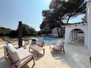 A poolside area with lounge chairs, a table, and a pergola structure. - Air-conditioned villa with private pool and large garden (Port d'Addaia)