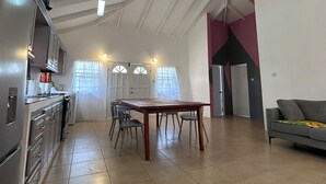 A spacious kitchen with modern appliances, a dining area with a wooden table and chairs, and a living area with a sofa.