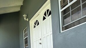 A hallway with a white door, a chair, and a rug.