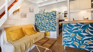 Un interior moderno con una escalera de madera, un sofá con cojines amarillos, una partición con diseño y una zona de cocina.