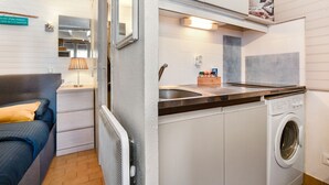 Una cocina compacta con lavadora integrada, un lavabo y una pequeña encimera.