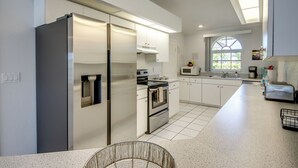 A modern kitchen with stainless steel appliances, white cabinetry, and a large window providing natural light. - Heated Pool - Gulf Access WIDE canal with dock - BBQ - Large Backyard (Cape Coral)