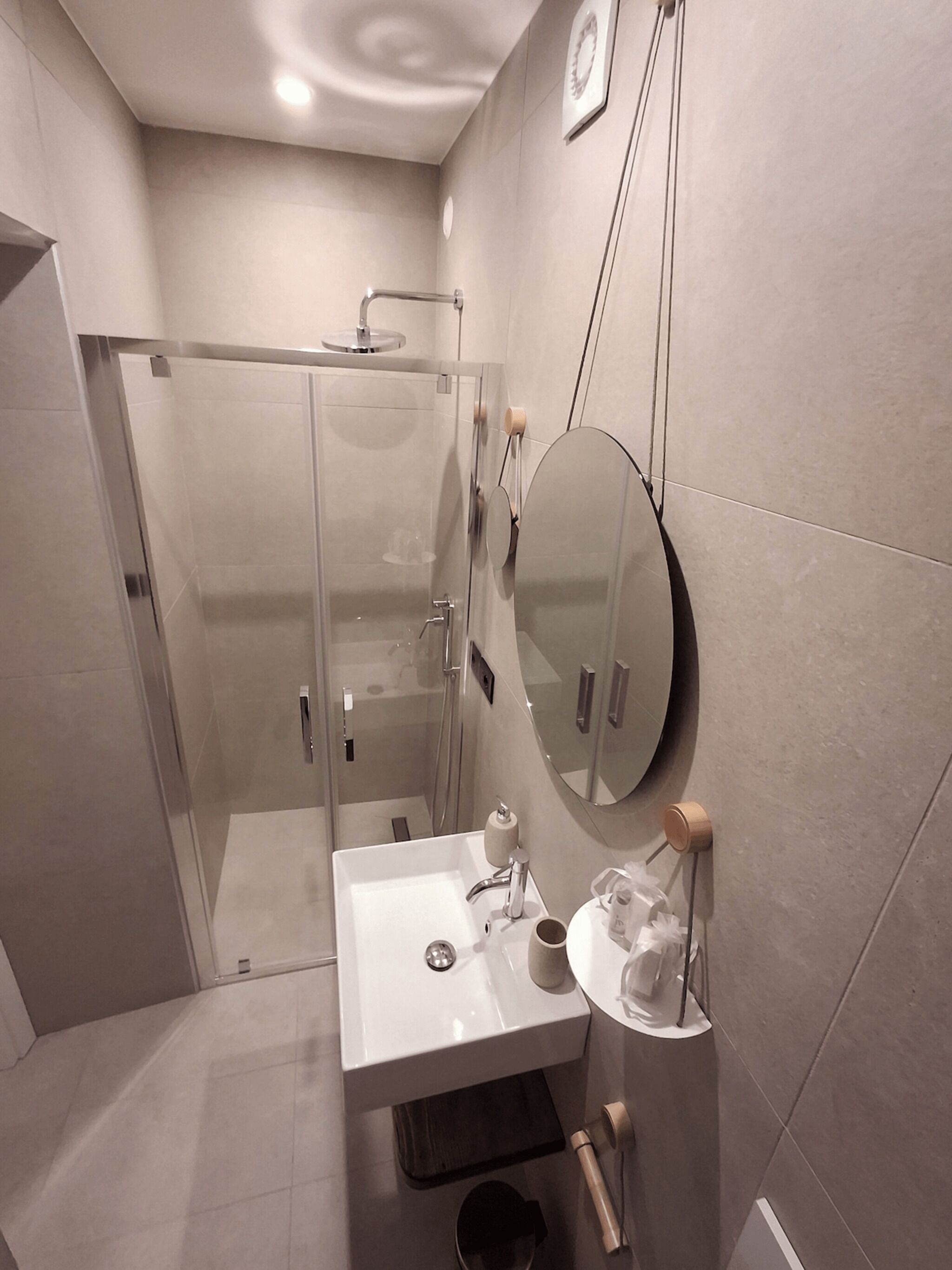 Une salle de bain moderne avec une douche à parois de verre, un lavabo blanc avec un miroir et des toilettes.
