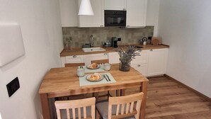 A modern kitchen with white cabinets, a wooden dining table, and two chairs. - Bottino Palace - Vulsinia House (BOLSENA)