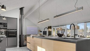 A modern kitchen with a large island, built-in appliances, and pendant lighting. - 5 Star Holiday Home in Norre Nebel (Norre Nebel)