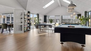 A spacious room with a pool table, a dining area, and a bookshelf. - 5 Star Holiday Home in Norre Nebel (Norre Nebel)
