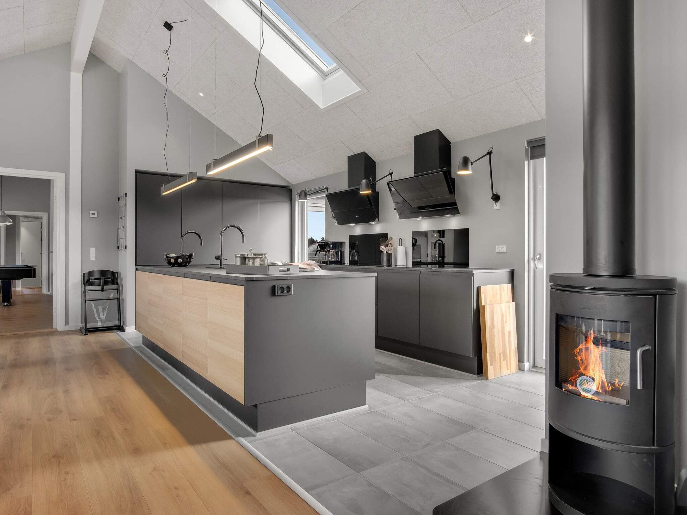 A modern kitchen with a central island, built-in appliances, and a wood-burning stove.