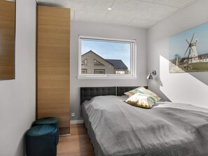 A bedroom with a bed, a window, and a view of a house. - 5 Star Holiday Home in Norre Nebel (Norre Nebel)