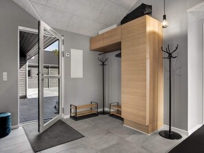 A modern interior with a wooden reception desk, coat hooks, and a bench. - 5 Star Holiday Home in Norre Nebel (Norre Nebel)