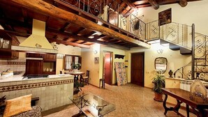 Una cocina amplia con techo de madera, un comedor con mesa de vidrio y una escalera con barandillas decorativas.