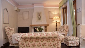 A living room with floral-patterned furniture, a fireplace, and a lamp.