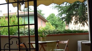 A balcony with a yellow awning, a table, and chairs.